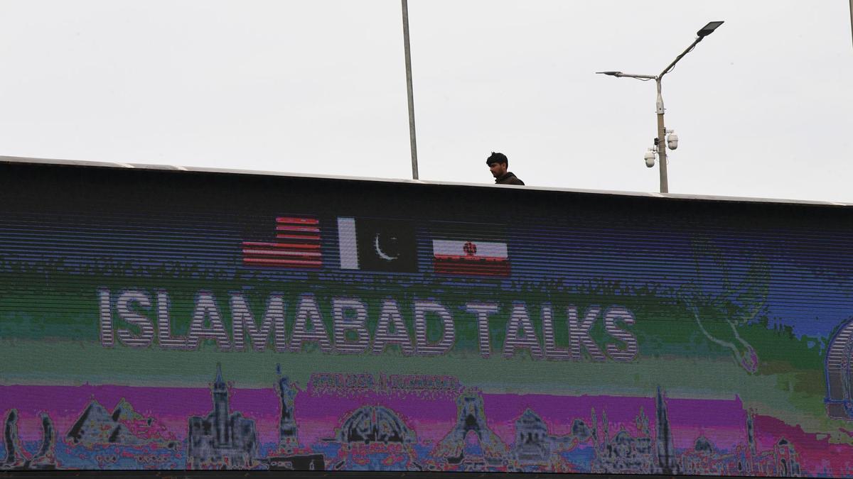 Un hombre pasa junto a una valla que anuncia las conversaciones entre EEUU e Irán en Islamabad (Pakistán)