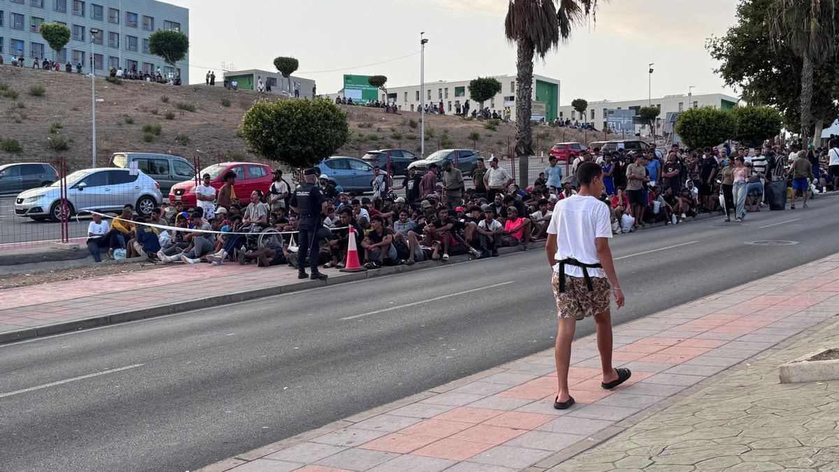 Cientos de migrantes hacen cola frente al campamento de Loma Colmenar tras ser expulsados por la policía para evitar avalanchas.