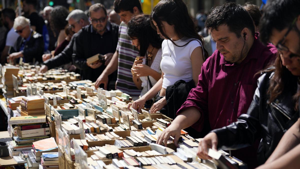 Varias personas buscan libros en una parada en el Paseo de Gracia de Barcelona durante la Diada de Sant Jordi.