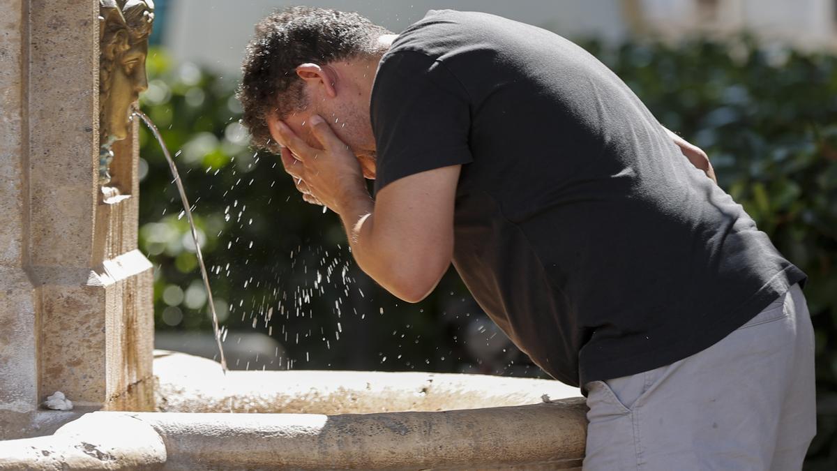 Un hombre se refresca en una fuente pública durante este miércoles en el que el calor sigue siendo sofocante en el país.