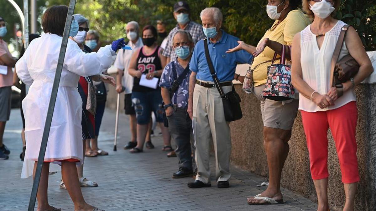Varias personas esperan su turno para las pruebas aleatorias de PCR en el Centro de Salud Abrantes en el distrito de Carabanchel en Madrid.