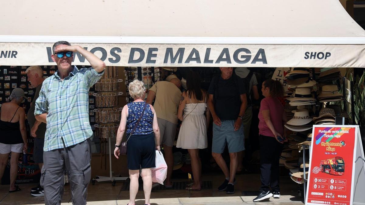 Varias personas se protegen del sol en una calle de Málaga. A 27 de junio de 2025.