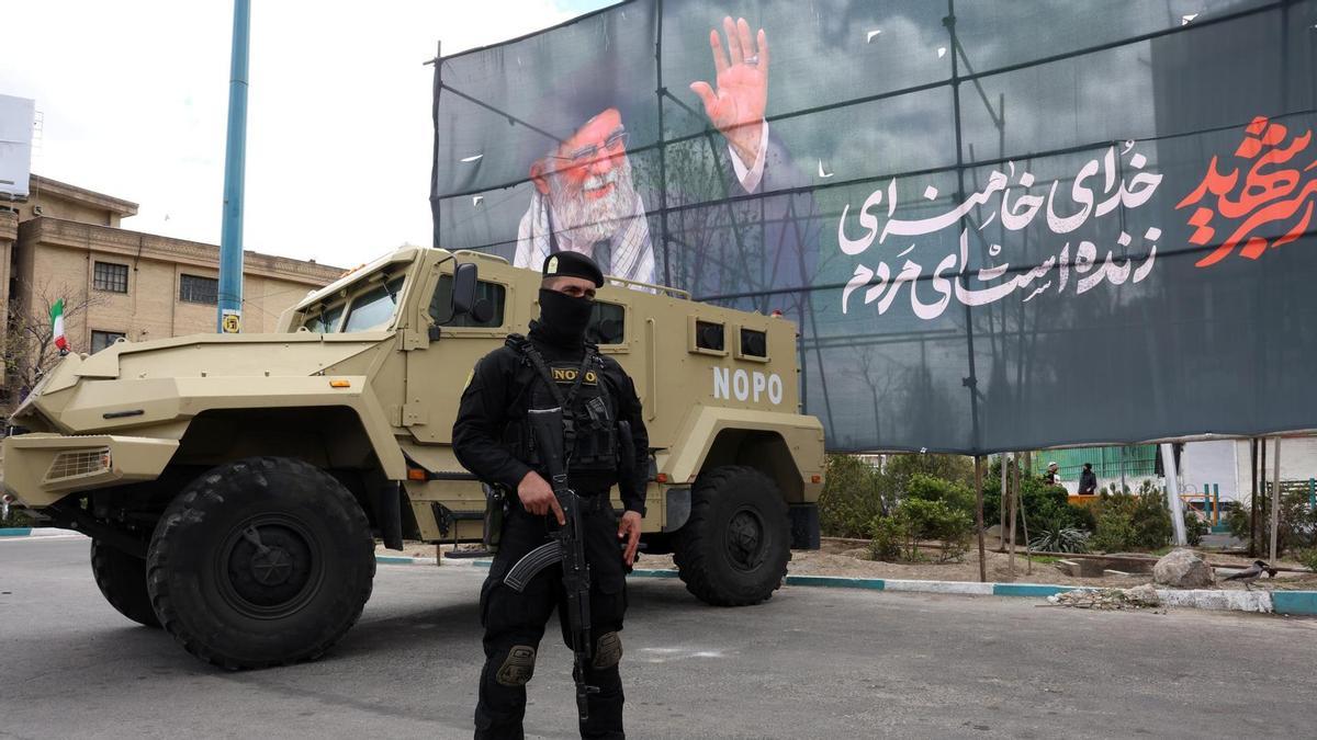 Un miembro de las fuerzas de seguridad iraníes monta guardia junto a una pancarta en honor al exlíder supremo iraní Ali Khamenei, en Teherán.