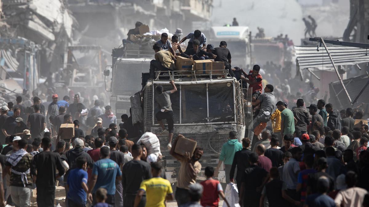 Palestinos alrededor de los camiones con ayuda humanitaria que llegaron este sábado a Jan Yunis, en el sur de la Franja de Gaza.