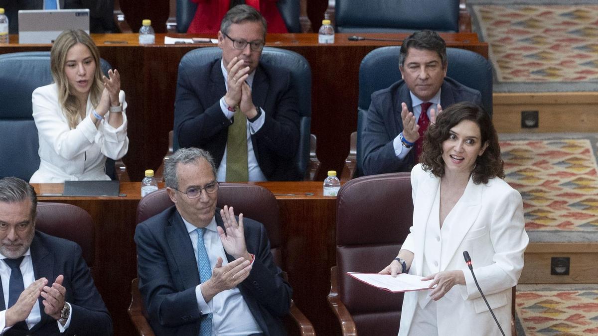 La presidenta de la Comunidad de Madrid, Isabel Díaz Ayuso, en la Asamblea de Madrid, en 2023. Junto a ella están Alfonso Serrano y Enrique Ossorio, dos de los beneficairios del bono.
