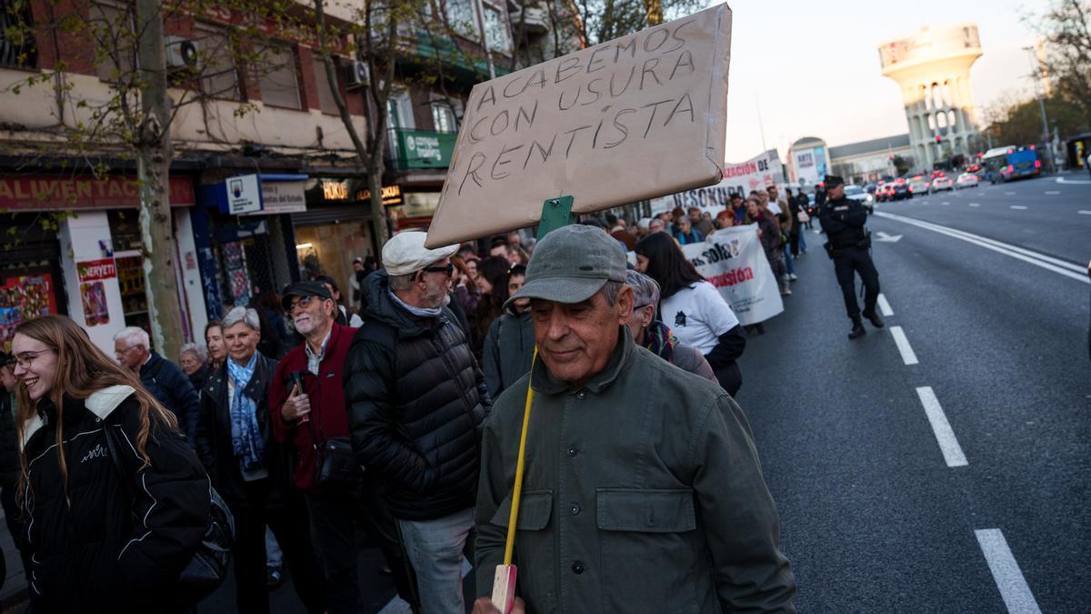 Una persona muestra un cartel durante la manifestación contra el negocio de la vivienda, en Madrid.