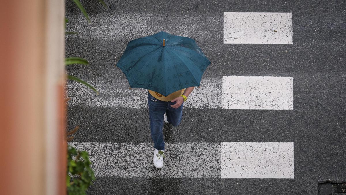 Un hombre se protege de la lluvia en La Foia, en Elx.