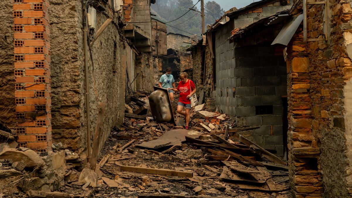 Dos vecinos entre las casas calcinadas de la aldea de San Vicente, este lunes en Vilamartín de Valdeorras (Ourense).