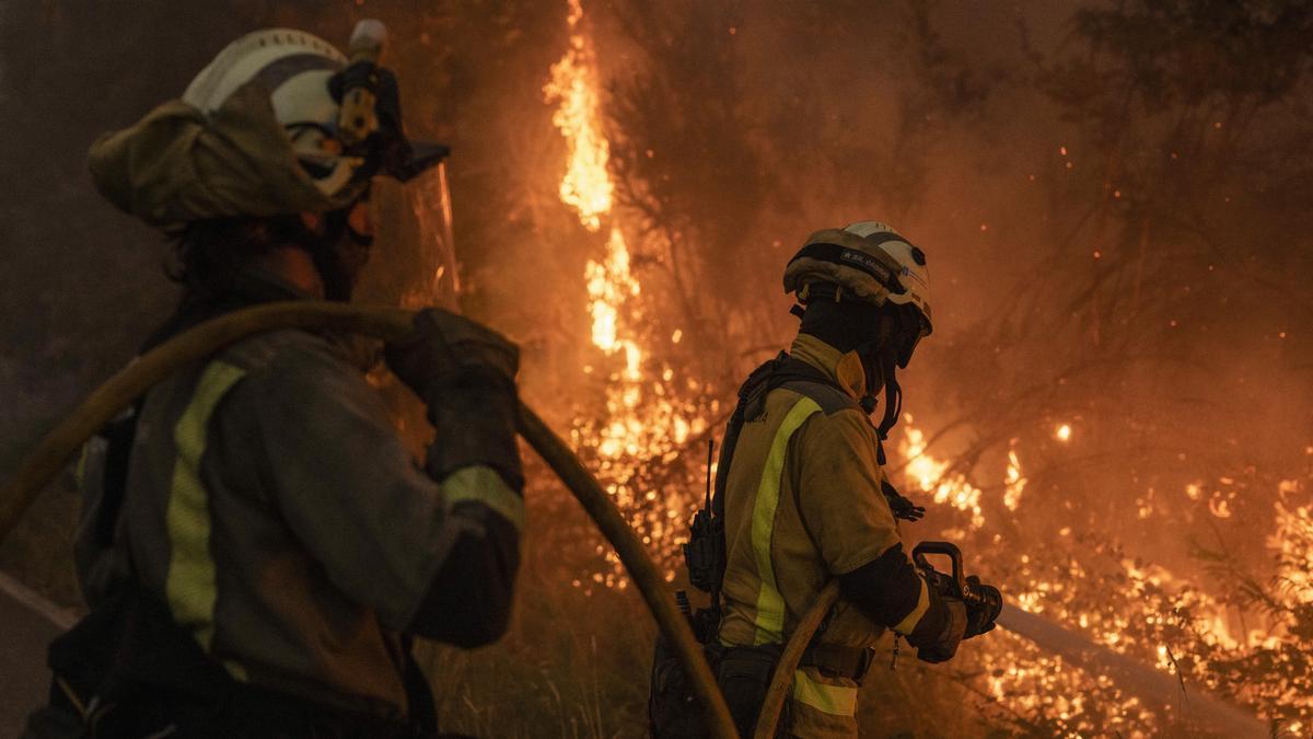 Dos bomberos durante las labores de extinción del incendio forestal que permanece activo este miércoles en As Neves (Pontevedra), el 7 de agosto.