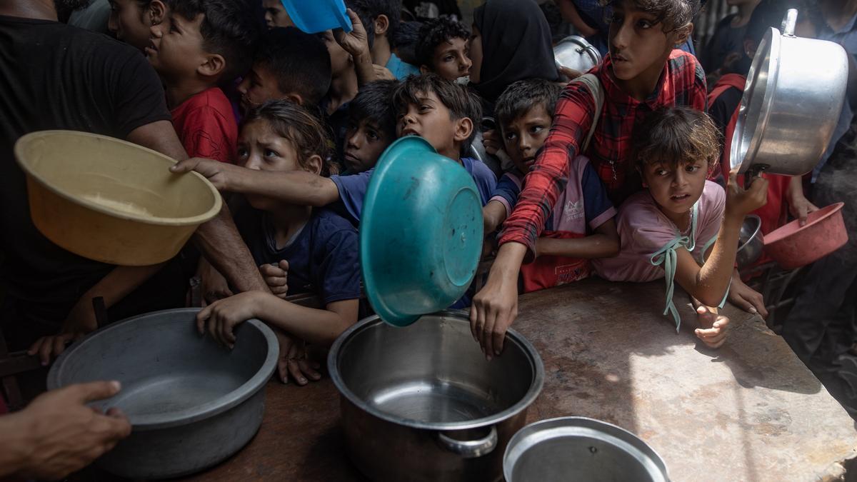 Cientos de menores se agolpan en un comedor social en la ciudad de Gaza para recibir sus raciones limitadas de alimentos.