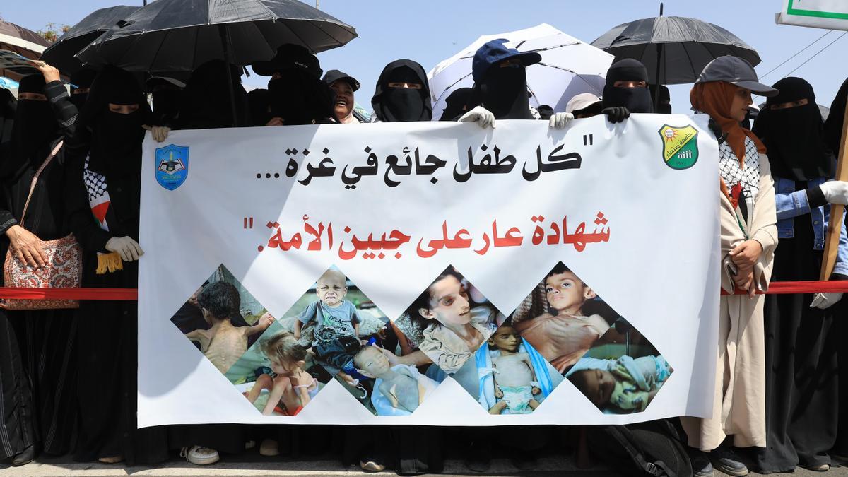 Manifestantes sostienen una pancarta que muestra a niños palestinos con desnutrición severa durante una manifestación para exigir el fin de la guerra en Gaza, en la Universidad de Saná, Yemen.