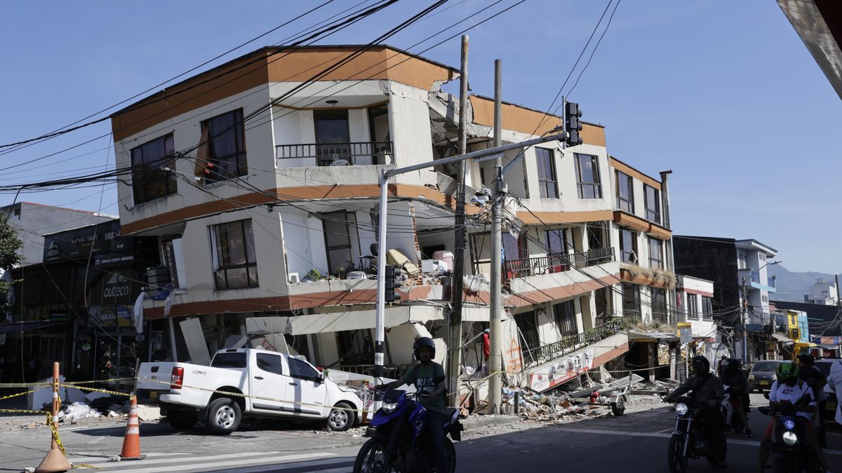 Personas transitan en motocicletas frente a una edificación destruida tras el terremoto en Pereira (Colombia).