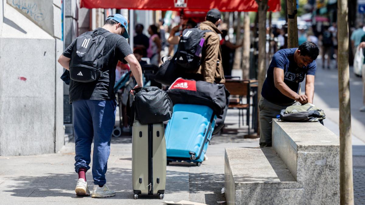 Varios turístas caminan con maletas en Madrid.