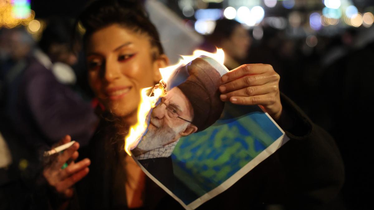 Una mujer quema una imagen del Líder Supremo de Irán, Alí Jamenei.