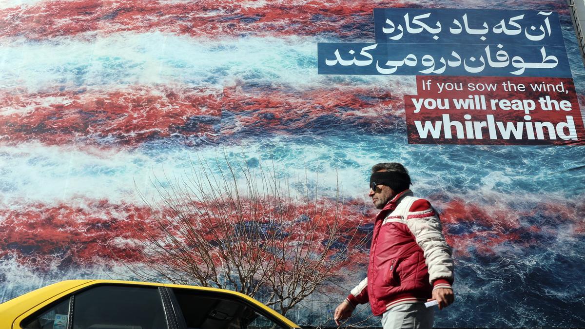 Iraníes caminan junto a una enorme valla publicitaria antiestadounidense en una calle de Teherán (Irán).