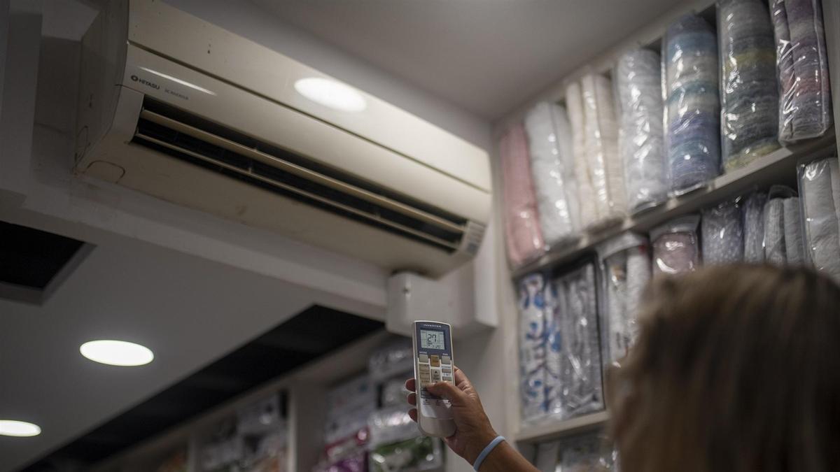 Una trabajadora pone el aire acondicionado a 27 grados, a 10 de agosto de 2022, en Barcelona.