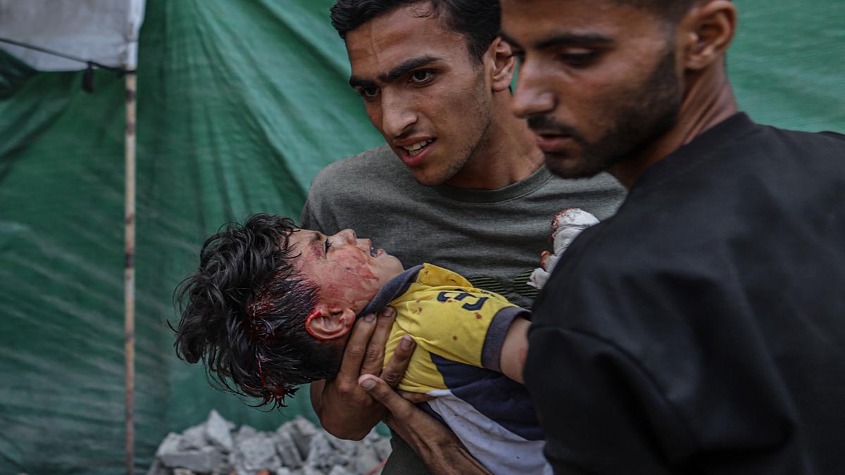 Dos jóvenes trasladan a un niño herido en un ataque aéreo israelí en Gaza.