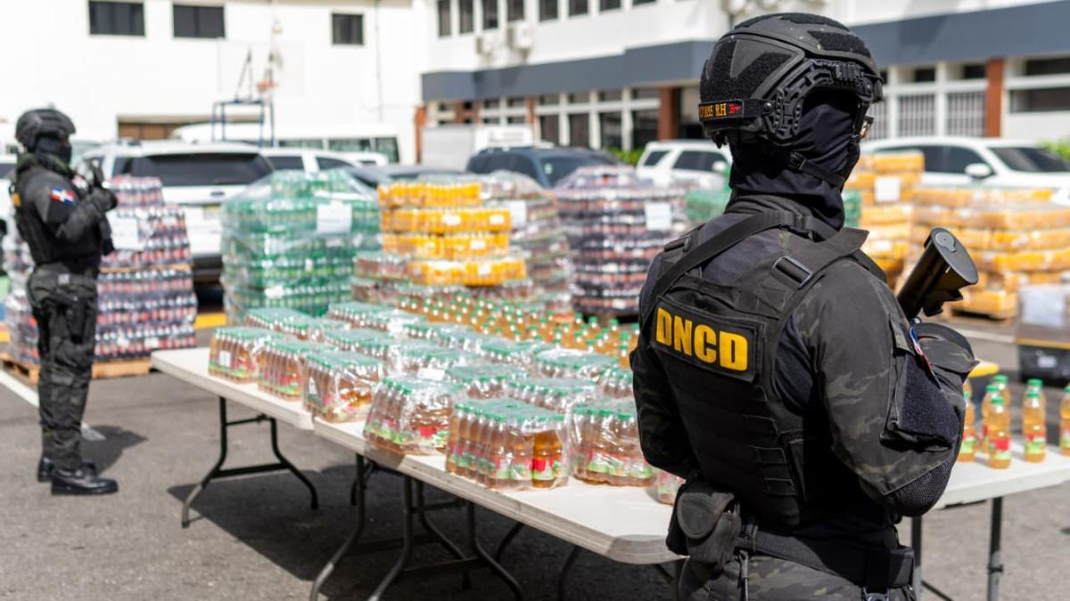 miembros de la DNCD junto a botellas