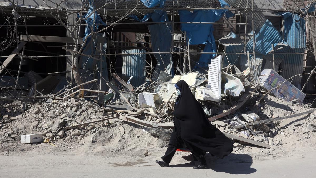 Una mujer iraní camina junto a un edificio dañado en el centro de Teherán (Irán).