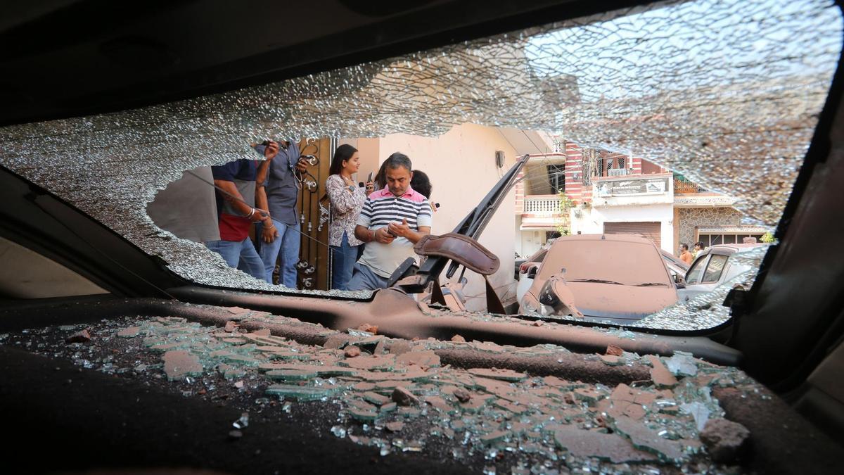 Ciudadanos indios se reúnen alrededor de un vehículo dañado tras un bombardeo transfronterizo procedente de Pakistán.