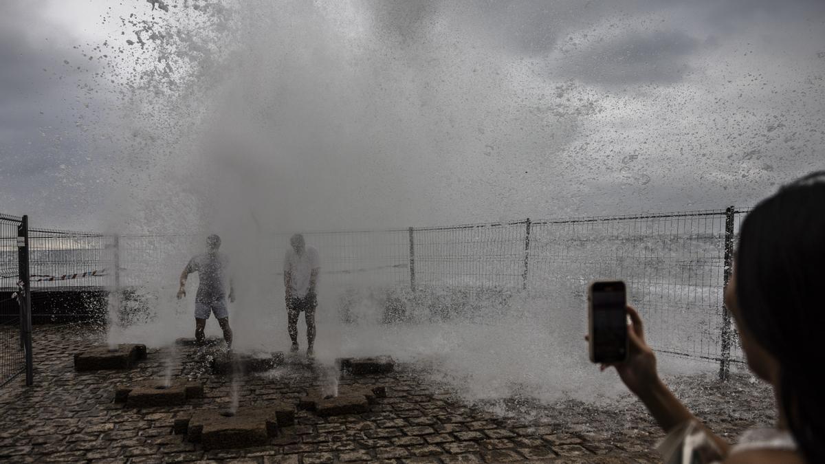 Dos turistas son sorprendidos por el oleaje registrado este martes en San Sebastián.