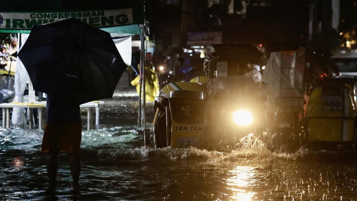 Filipinos vadean las aguas de una carretera inundada en Manila, Filipinas, el 22 de septiembre de 2025.