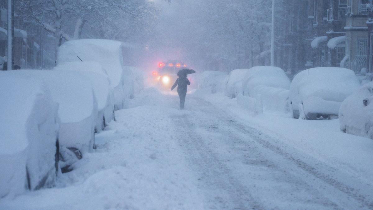 Una persona camina por la calle delante de un vehículo quitanieves en el barrio de Brooklyn, Nueva York.