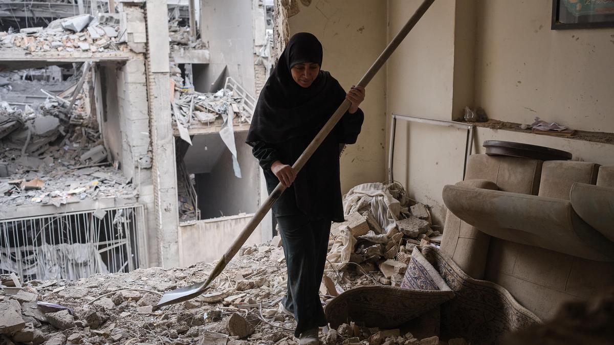 Una mujer trata de limpiar una vivienda en el barrio de Haft Chenar de Teherán que resultó dañada en un ataque de Estados Unidos e Israel.