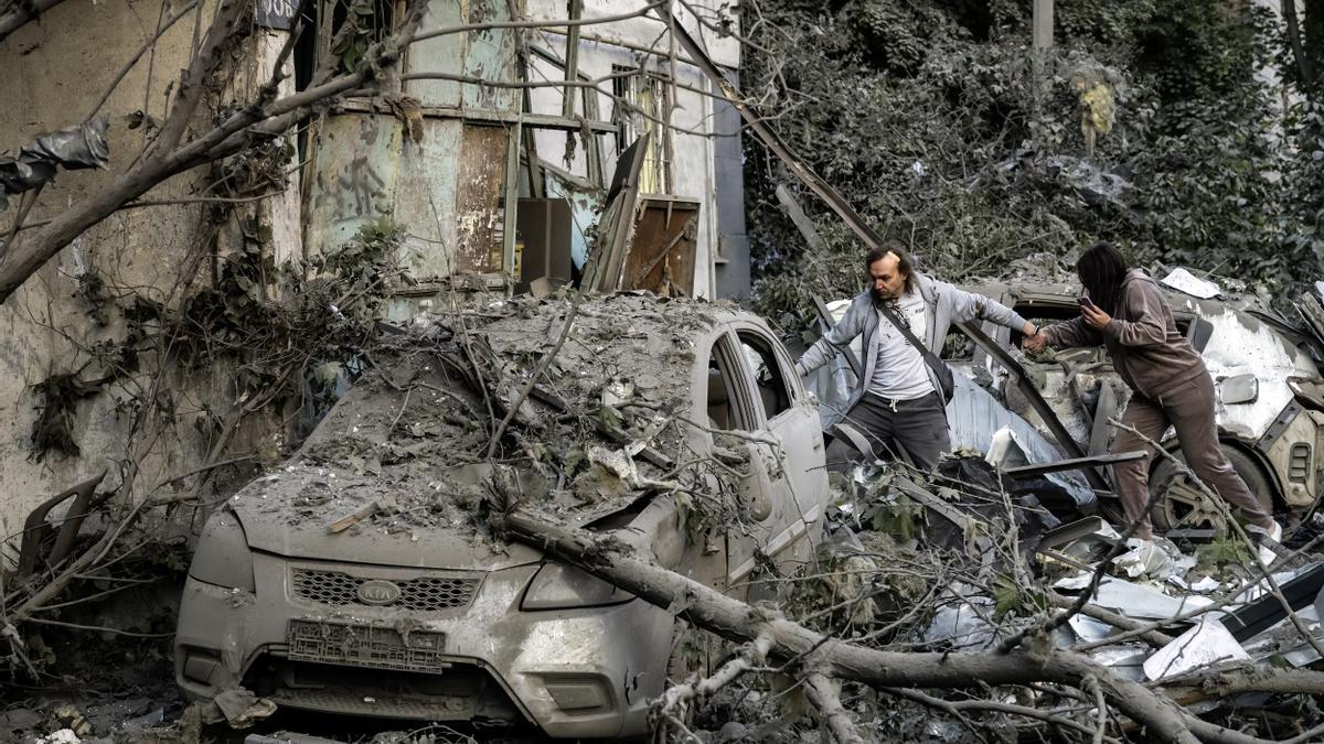 Personas intentan llegar a sus apartamentos en el lugar de un ataque ruso contra una zona residencial en Kiev.