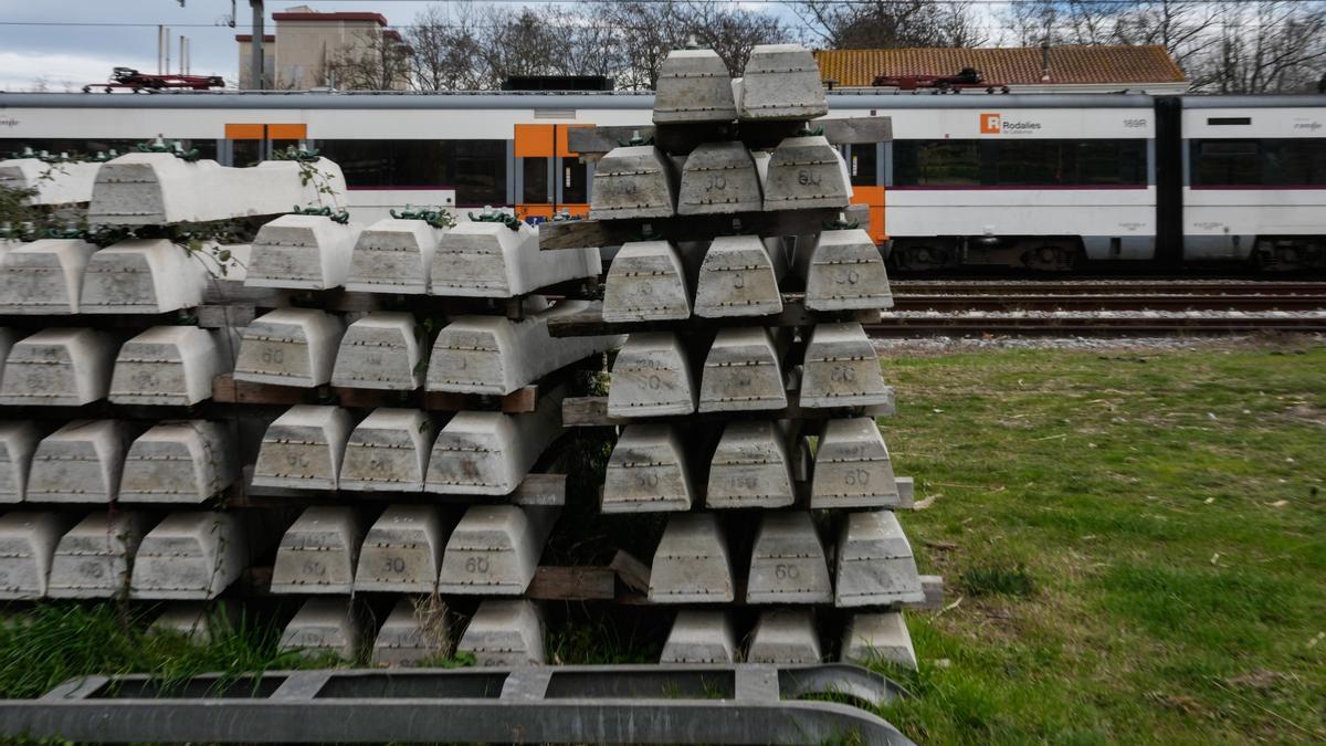 Vista de un tren parado junto a un cargamento de traviesas en la línea R1 de Rodalies.