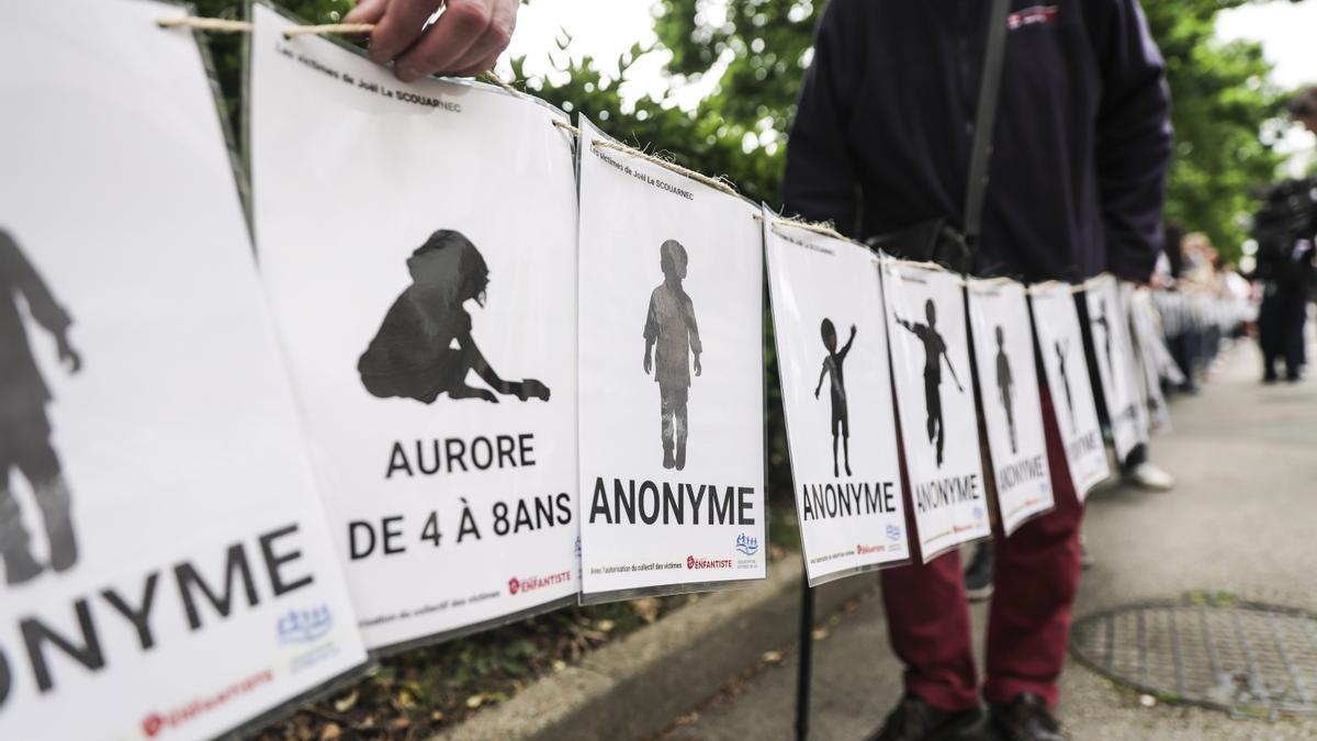Personas, incluidas víctimas, portan pancartas que representan a las víctimas de Joel Le Scouarnec en el día del veredicto del juicio del cirujano francés en Vannes, Francia.
