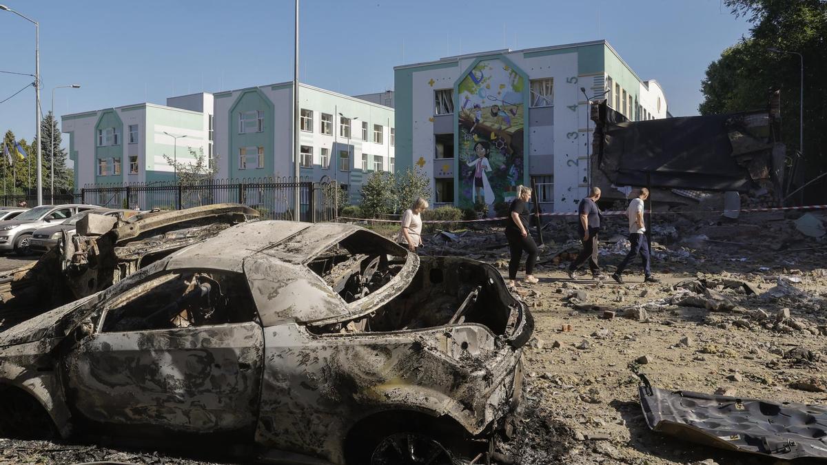 Vecinos caminan por una zona dañada con coches destruidos cerca de un edificio escolar tras un ataque aéreo ruso en Kiev, Ucrania, 4 de julio de 2025.