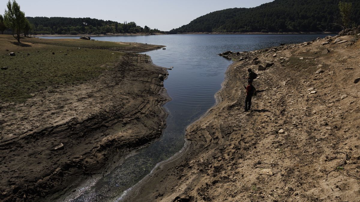 Dos hombres pescan en el bajo nivel de agua en el embalse de La Jarosa en Guadarrama, Madrid.