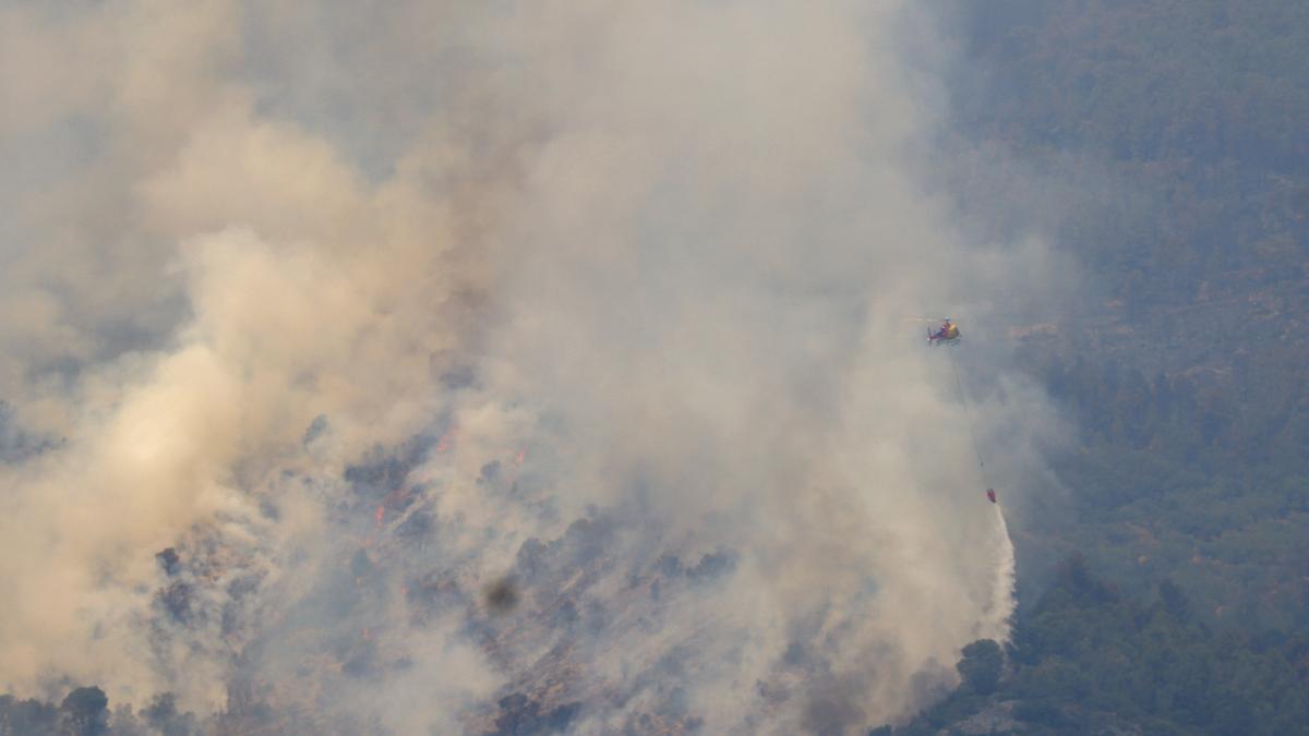 Un helicóptero trabaja en la tareas de extinción del incendio forestal de alta intensidad en Paüls (Tarragona).