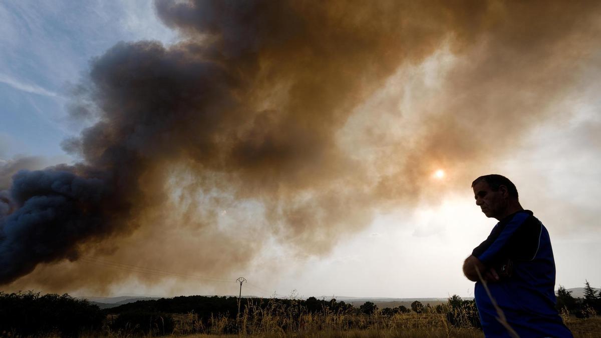 Una persona junto a una columna de humo del incendio de Las Navas del Marqués (Ávila), este viernes.