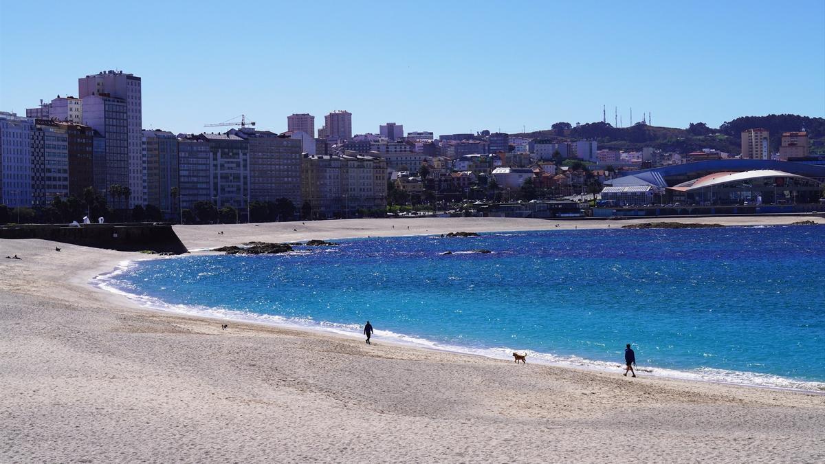 Varias personas caminan por la orilla de las playas Orzán y Riazo, en A Coruña, Galicia (España)