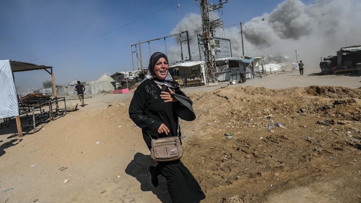 Una mujer palestina corre a refugiarse durante un ataque aéreo israelí en Ciudad de Gaza..