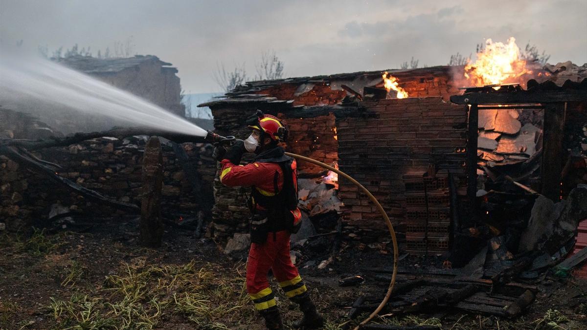 Un bombero trata de extinguir, manguera al hombro, el incendio en Abejera, Zamora.