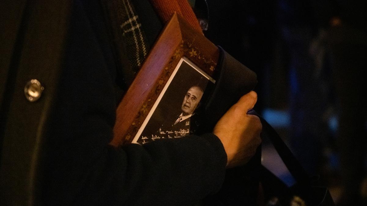Una persona lleva un retrato de Francisco Franco, a la salida de la misa funeral en recuerdo de Francisco Franco