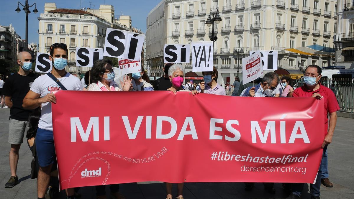 Un grupo de personas se reúne sosteniendo pancartas y carteles durante la concentración de la asociación Derecho a Morir Dignamente (DMD) en la Puerta del Sol, a 25 de junio de 2021, en Madrid, (España).