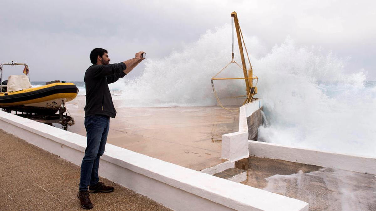 Un hombre fotografía el oleaje en el paseo marítimo de la urbanización S'Algar, en el municipio de Sant Lluís (Menorca).
