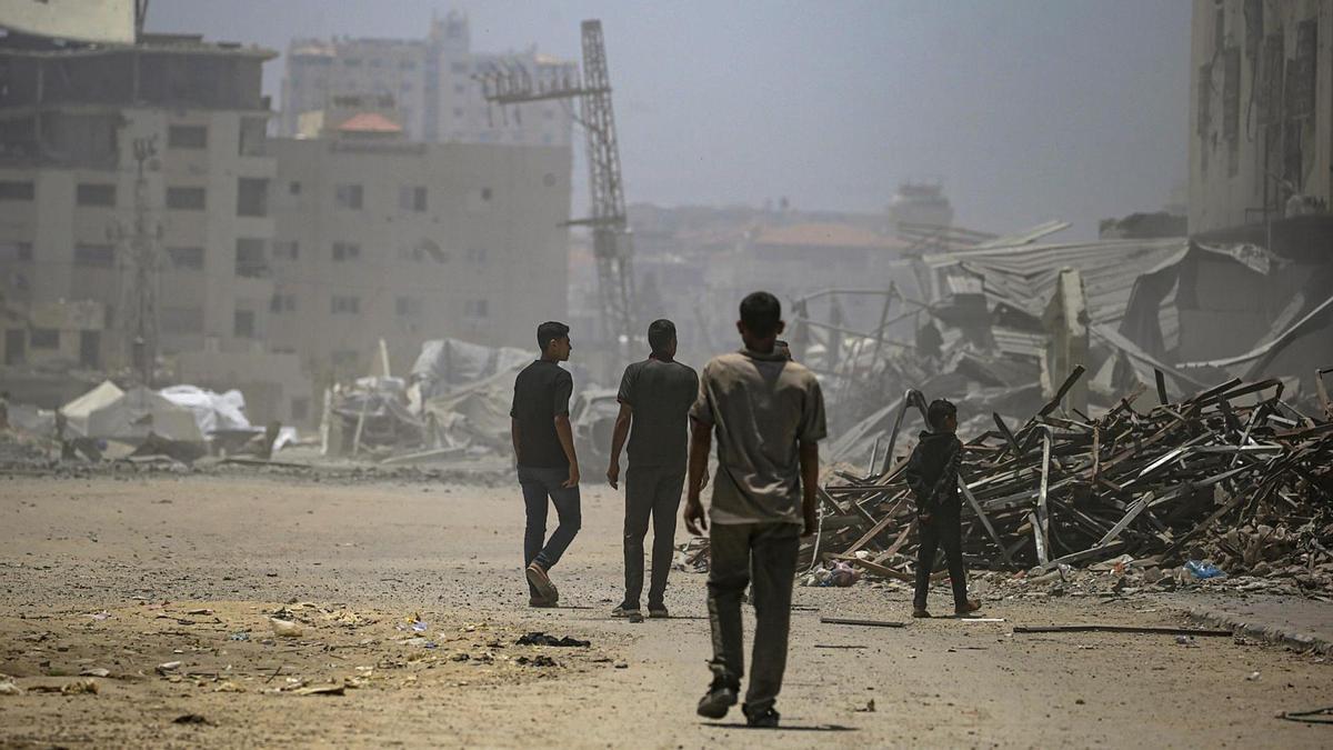 Palestinos desplazados inspeccionan un edificio destruido tras un ataque aéreo israelí al oeste de Ciudad de Gaza.