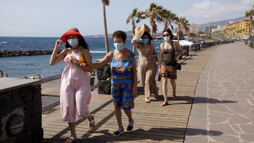 Un turistas caminan por un paseo cercano a la playa de Las Caletillas, en el municipio de Candelaria (Tenerife).