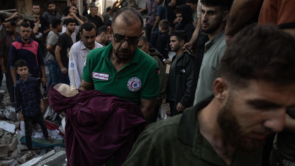 Palestinos recuperan el cuerpo de un bebé mientras buscan los cuerpos de personas desaparecidas bajo los escombros de un edificio.