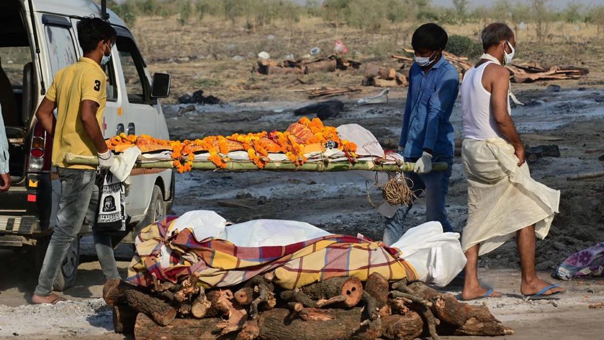 Miembros de la familia y paramédicos llevan los cuerpos de las víctimas que murieron a causa de la enfermedad covid-19 a los lugares de cremación en Phaphamau Ghat (India).