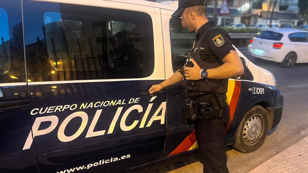 Un agente de la Policía Nacional junto a una furgoneta policial.
