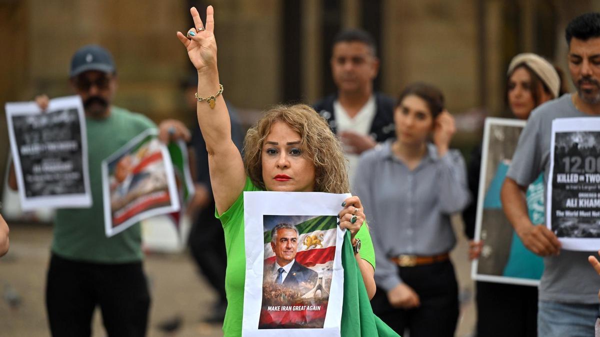 Un manifestante sostiene un retrato de Reza Pahlavi, el hijo exiliado del último sha de Irán, hace el signo de la victoria durante una manifestación.