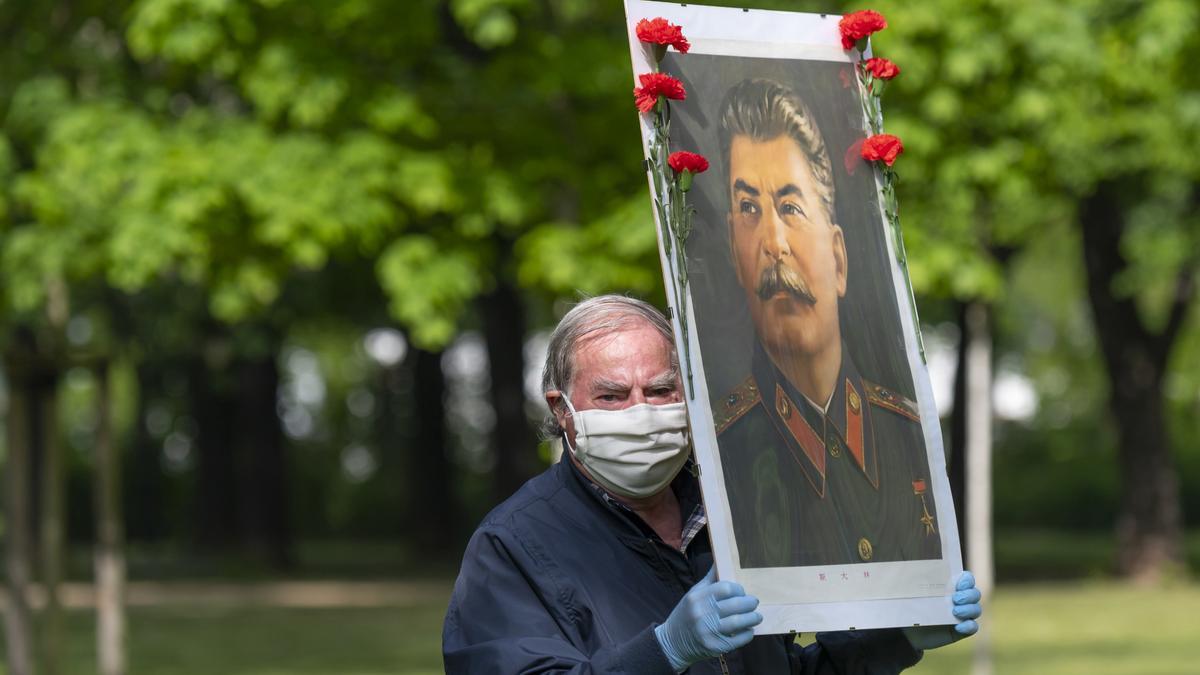 Archivo - Un hombre sostiene un retrato del líder soviético Joseph Stalin.