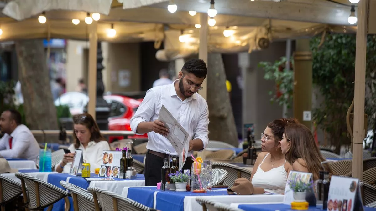 Un camarero de origen extranjero atiende una mesa de un bar en Barcelona.