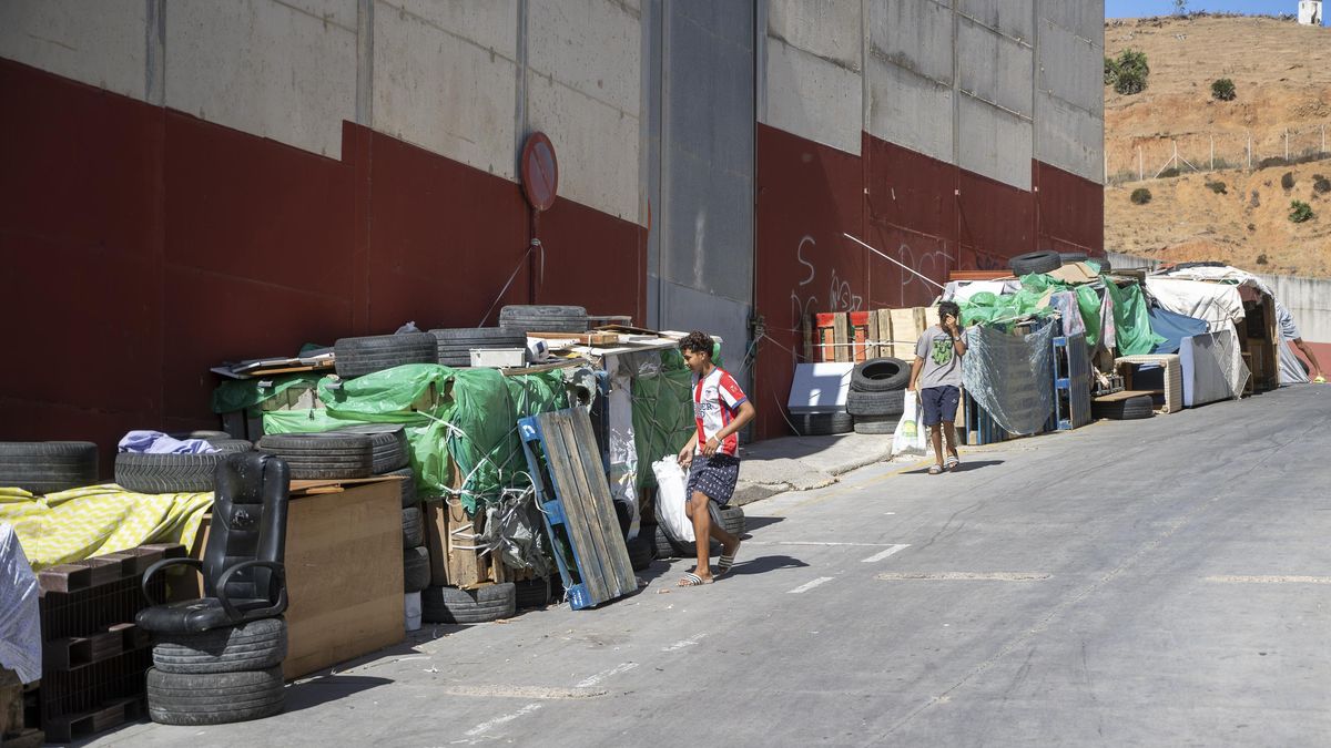 Dos jóvenes buscan plásticos y tablas para reforzar sus chabolas en el polígono de El Tarajal.